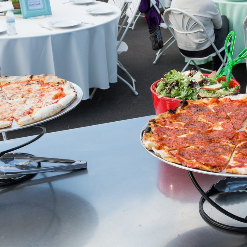 Two Versalia pizzas, one cheese and one pepperoni, with a bowl of salad on a buffet table.